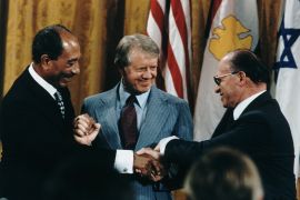الرئيس الأمريكي جيمي كارتر يتوسط الرئيس المصري أنور السادات ورئيس الوزراء الإسرائيلي مناحم بيغين (غيتي)