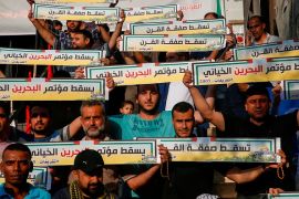 فلسطينيون في غزة يحملون لافتات مناهضة لورشة البحرين