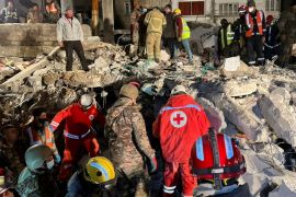 Rescuers search for survivors at the site of a damaged building in the Syrian city of Jableh