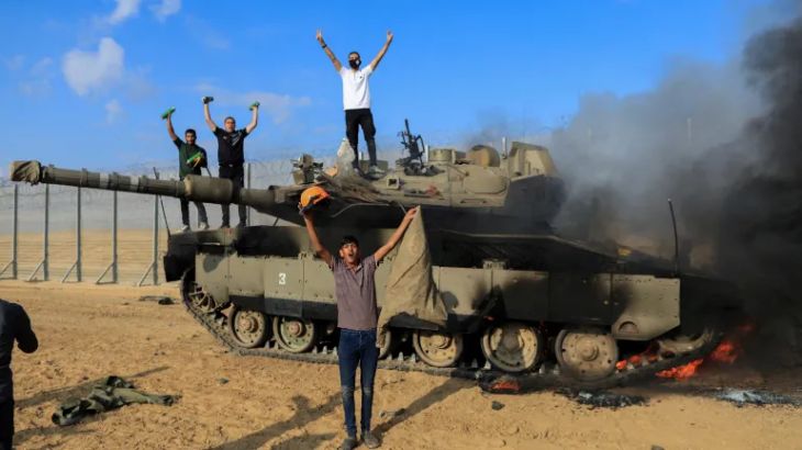 فلسطينيون يحتفلون فوق دبابة إسرائيلية دمرتها المقاومة الفلسطينية (رويترز)