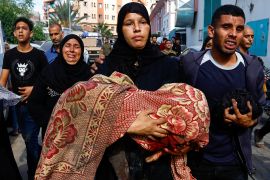 فلسطينية في خان يونس تحمل جثمان طفل شهيد (رويترز)