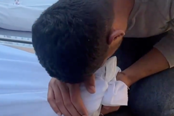 شاب يقبل قدمي والدته الشهيدة جراء القصف الإسرائيلي لقطاع غزة