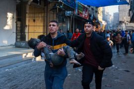 فلسطيني يحمل طفلا مصابًا بعد استئناف القصف الإسرائيلي على رفح جنوب قطاع غزة (الفرنسية)
