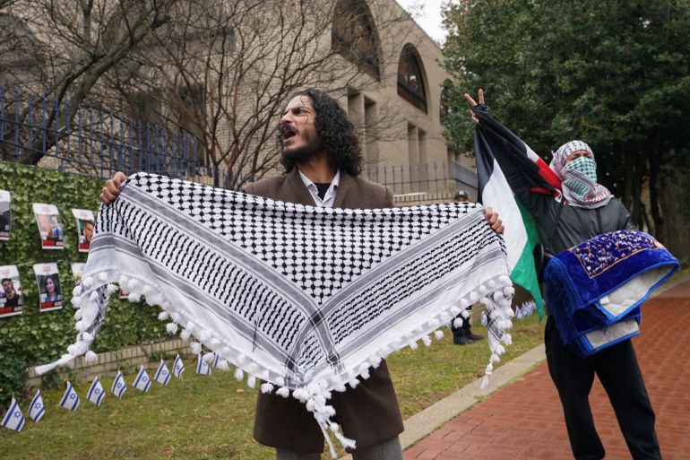 متظاهر يرفع الكوفية الفلسطينية في احتجاج أمام السفارة الإسرائيلية في واشنطن