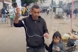 أب يسير في شارع بقطاع غزة حاملا المحلول لطفله