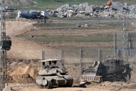 دبابة وجرافة مدرعة تسيران على طول الحدود بين إسرائيل وقطاع غزة (غيتي)