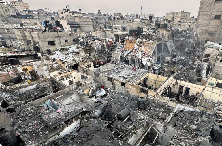 أشخاص يبحثون بين أنقاض المباني المتضررة في أعقاب غارة جوية إسرائيلية على منازل في غزة