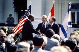 الرئيس الأمريكي جيمي كارتر (وسط) يهنئ الرئيس المصري أنور السادات (يسار) ورئيس الوزراء الإسرائيلي مناحيم بيغن (يمين) أثناء تصافحهما في 26 مارس 1979 في البيت الأبيض، بعد التوقيع على معاهدة السلام (الفرنسية)