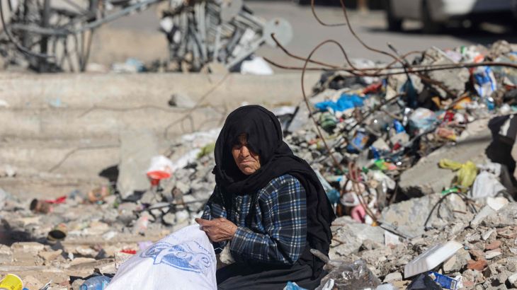 امرأة تنتشل أغراضا أشياء من تحت أنقاض المباني التي دمرها القصف الإسرائيلي في رفح