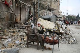 رجل غزاوي يجلس بجوار منزله المهدم جراء الغارات الإسرائيلية على قطاع غزة (رويترز)