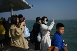 يلتقط السياح الصينيون صورًا للجزر التايوانية من مسافة كيلومترين خلال جولة بالقارب لمشاهدة الجزر، قبالة شيامن، في مقاطعة فوجيان جنوب شرقي الصين (الفرنسية)