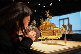 مواطنة صينية تستخدم عدسة مكبرة لمراقبة تفاصيل قطعة ذهبية في غرفة العرض بمتجر مجوهرات جنوبي الصين (الفرنسية)