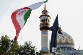 إيرانيون يرفعون علمًا ونموذجًا لصاروخ في ساحة فلسطين وسط طهران، احتفالًا بالهجوم على إسرائيل (الفرنسية)