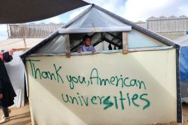 نازح يدوّن على الخيام عبارات شكر للطلاب الجامعيين المتضامنين مع غزة في أمريكا (الأناضول)